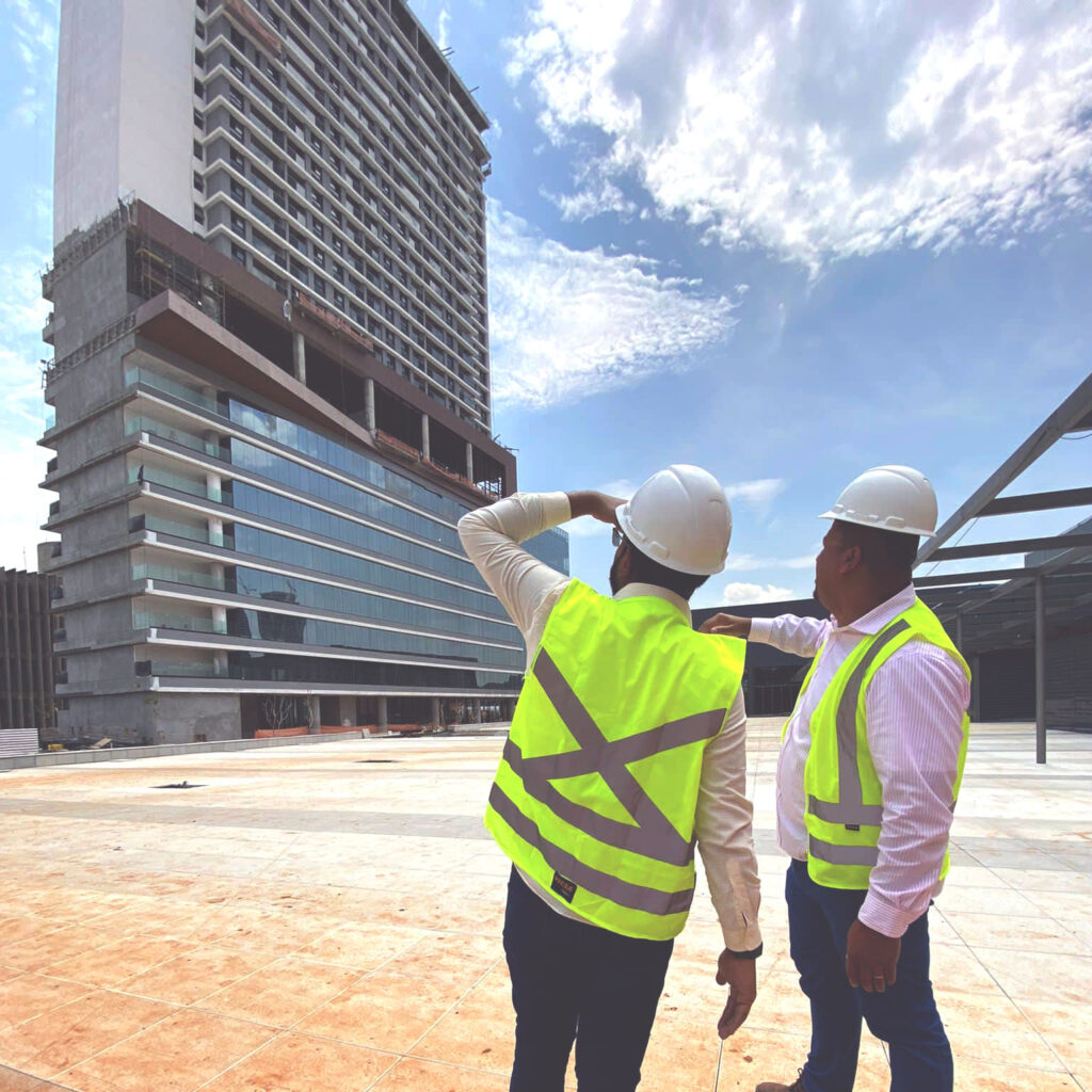 Dois trabalhadores observando obra de uma torre do complexo paseo alto das nações