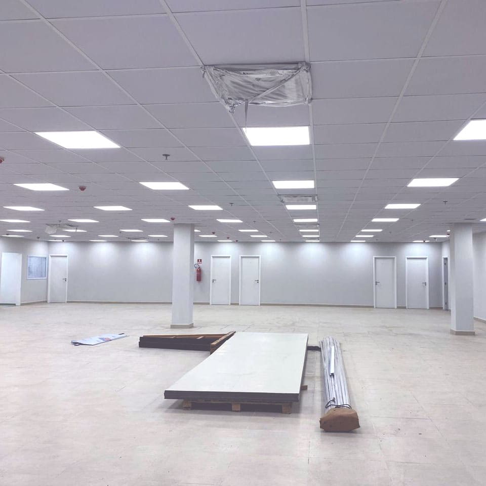 Sala grande com forros minerais instalados e materias para instalação no chão