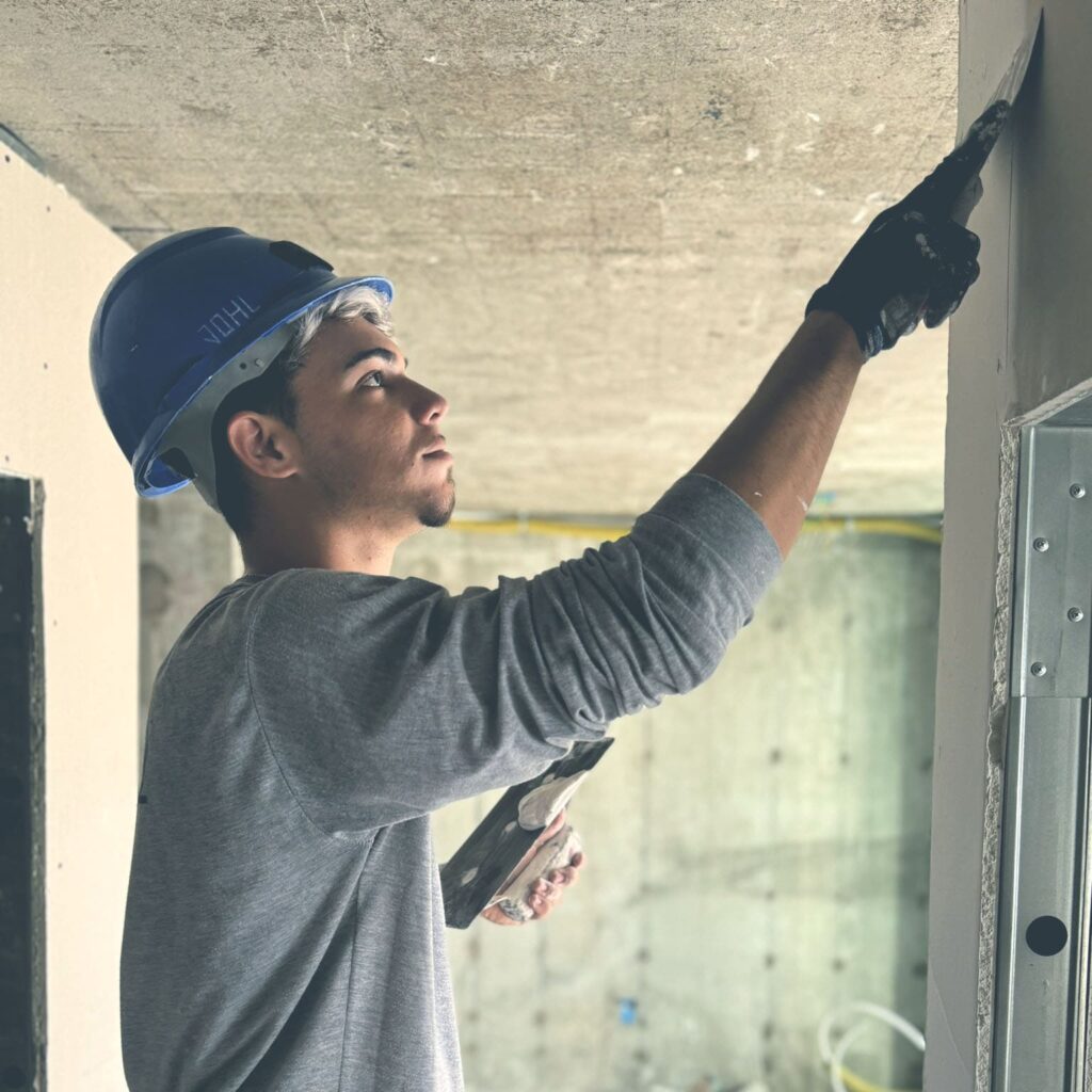 Homem passando massa de acabamento em parede de gesso